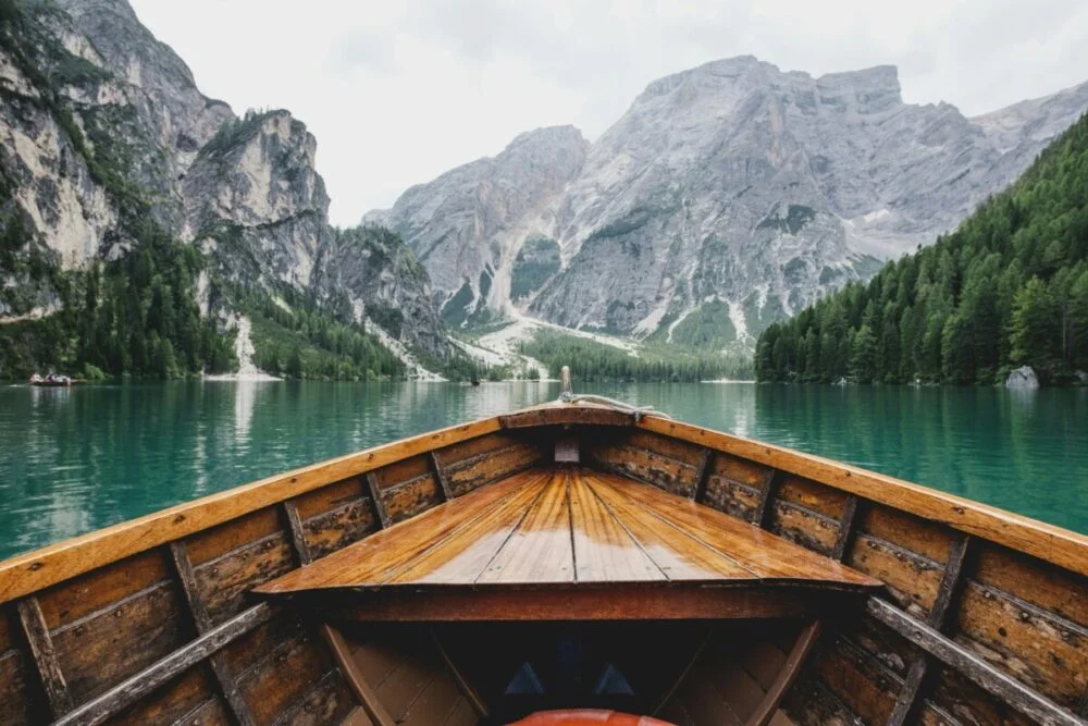 A wooden boat moving toward rugged mountains. the meaning of travel