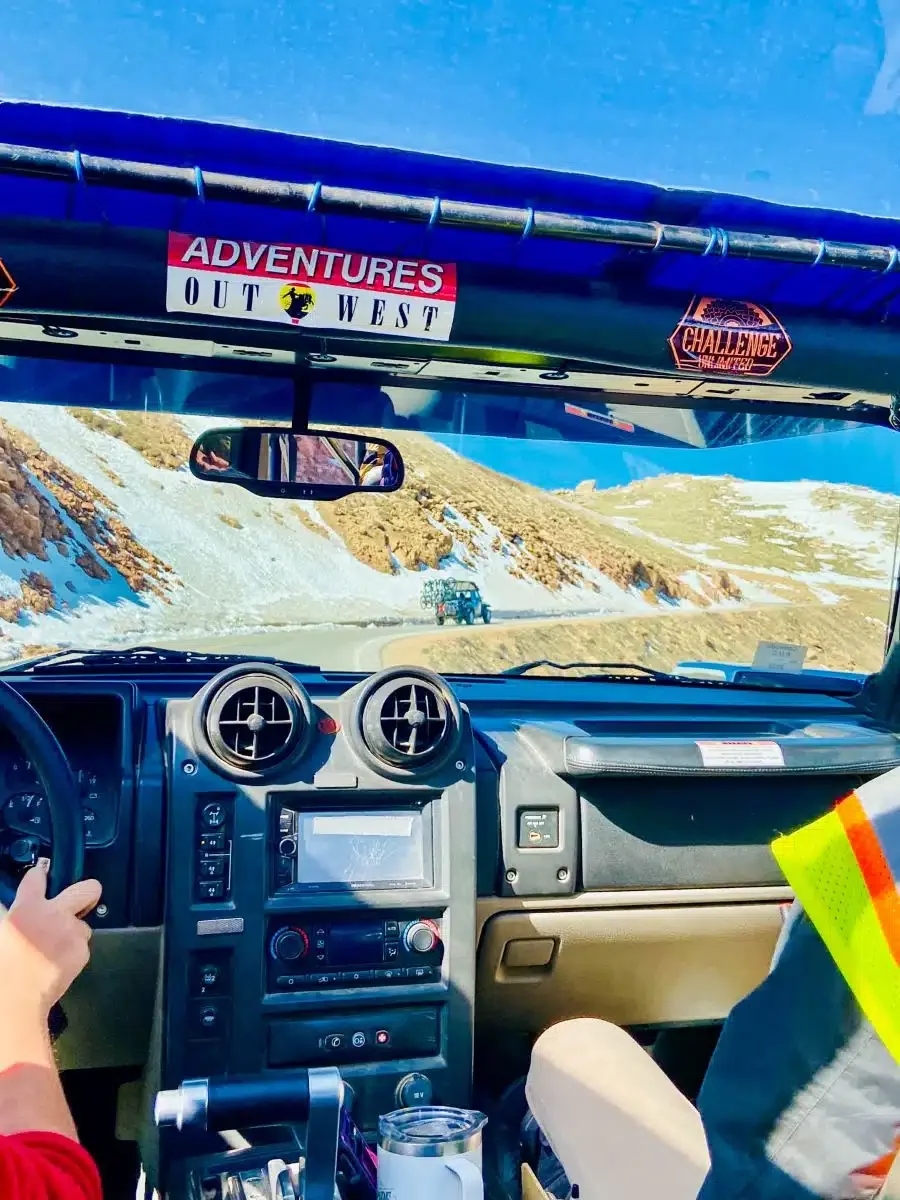 View from inside the vehicle on the drive up Pikes Peak, showing mountains and blue sky.