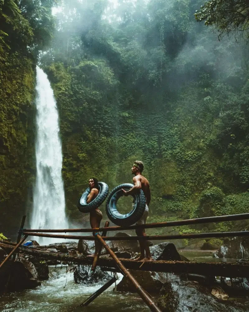 two people on a bridge looking at a waterfall
