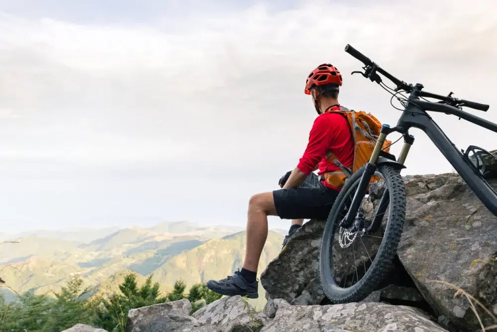 Mountain biker looking at inspiring landscape on bike rocky trail in autumn mountains. Riding on full suspension bike. Sport fitness, motivation and inspiration in beautiful inspirational landscape.