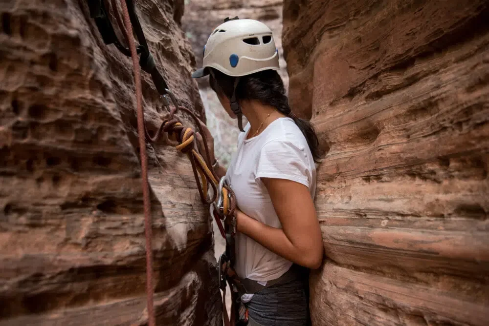 A canyoneer passing through a narrow slot canyon in Zion National Park