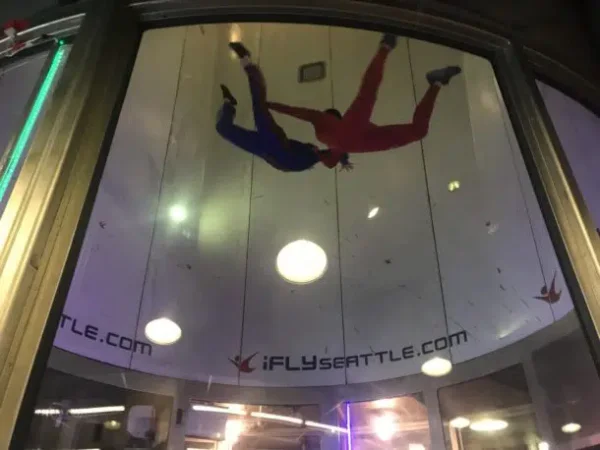 Two indoor skydivers floating high in the wind tunnel.