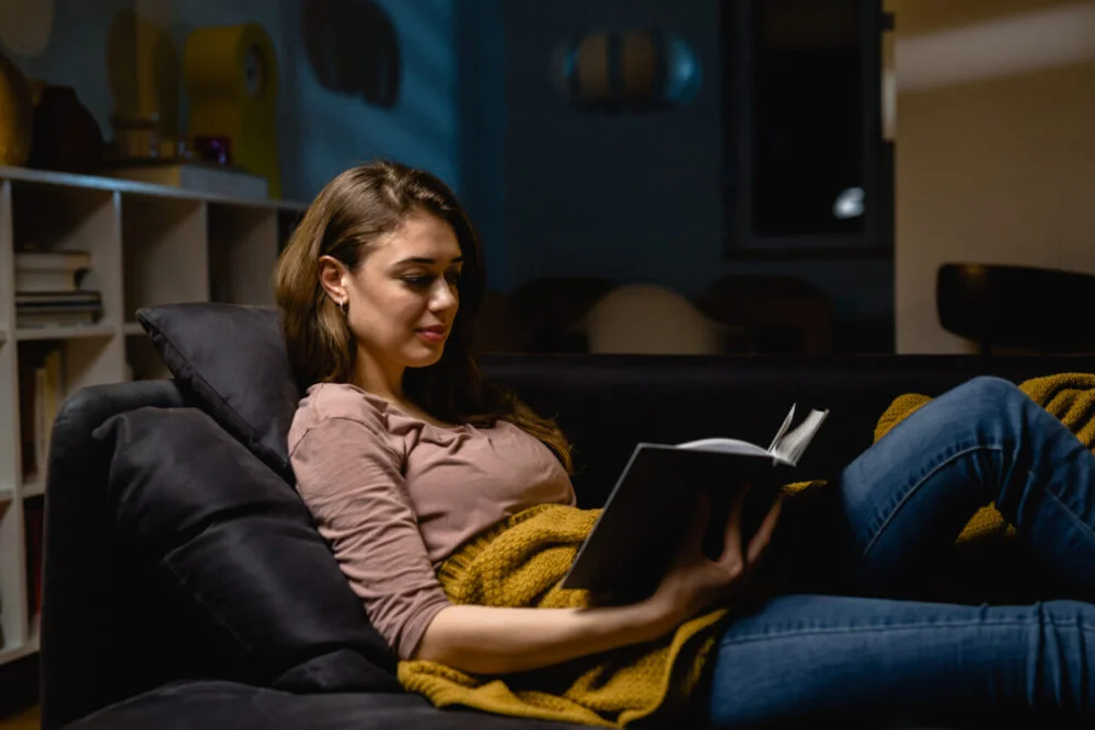 young woman relaxing at home reading book